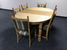 A circular blond oak extending dining table with leaf together with six chairs upholstered in green,