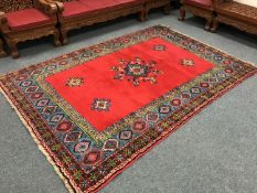 A woollen fringed eastern carpet of geometric design on red ground