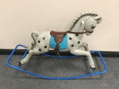 A mid-20th century plastic child's rocking horse with leather saddle