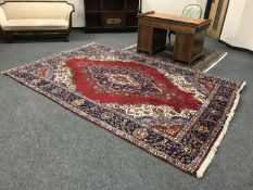 A Persian Tabriz carpet with large central medallion framed by blue border of meandering vines