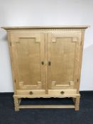 A blond oak double door cabinet fitted drawers beneath