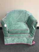 A contemporary tub chair upholstered in a turquoise fabric with pink piping