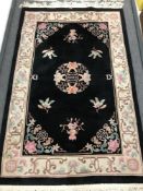 A fringed Chinese style rug on black ground