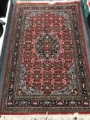 A fringed woollen rug on red ground