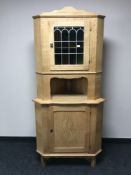 A blond oak corner display cabinet with stained leaded-glass door
