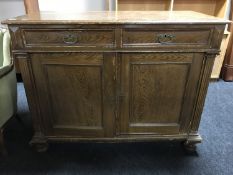 An early 20th century oak double door sideboard on bun feet