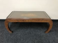 A carved oriental glass-topped coffee table