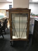 A walnut single door display cabinet on claw and ball feet