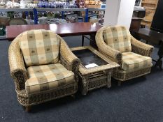 A pair of wicker conservatory armchairs and glass top coffee table
