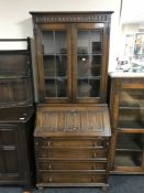 An oak linen fold bureau bookcase with leaded glass doors