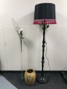 A black standard lamp with shade together with a tall glass vase containing dried flowers and a