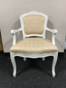A white framed salon armchair upholstered in peach fabric