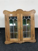 An oak double door wall cabinet with stained leaded glass doors