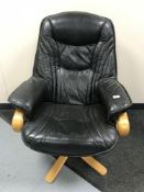 A late 20th century beech framed black leather swivel armchair