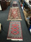 Four fringed woollen rugs on red ground