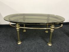 A mid 20th century oval brass coffee table with smoked glass top, 61 cm x 111 cm.