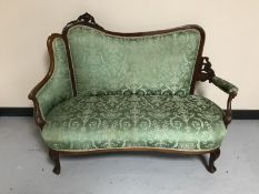 A carved Victorian mahogany drawing room settee upholstered in a green fabric