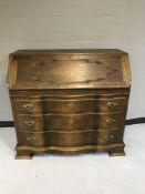 An early twentieth century oak serpentine fronted bureau fitted with three drawers
