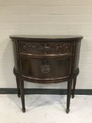 A carved mahogany demi lune side cabinet