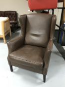 A mid twentieth century brown leather wing backed armchair