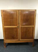 A mid twentieth century mahogany double door storage cupboard fitted with drawers and trays
