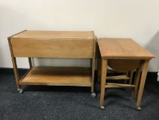 A mid-20th century teak drop leaf serving trolley together with teak table fitted three beneath