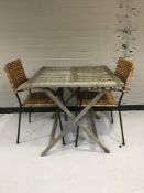 A folding teak garden table together with two wicker and metal garden chairs