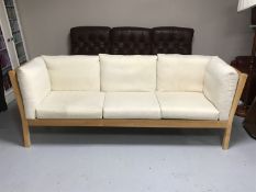 A beech framed three seater settee with beige cushions