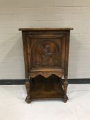 An early 20th century oak cabinet with a carved panel door