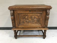 An early 20th century oak fall front cabinet with a carved panel door