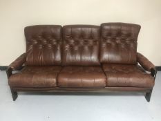 A wooden framed brown buttoned leather three seater settee