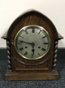 An oak cased arch topped mantel clock with barleytwist supports