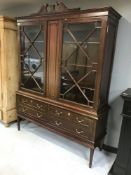 A contemporary mahogany double door glazed display cabinet on base fitted with four drawers