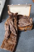 A vintage leather trunk containing three fur coats and a fur stole
