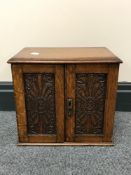 An Edwardian carved oak double door smoker's cabinet