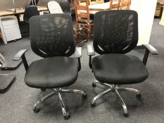 A pair of adjustable swivel office armchairs in mesh fabric