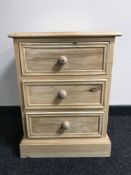 An unfinished reclaimed pine three drawer bedside chest
