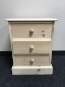 An unfinished pine three drawer bedside chest