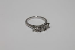 A platinum three stone diamond ring, the three brilliant cut stones within a claw setting,