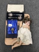 An early 20th century bisque headed doll, cased plated serving spoons,