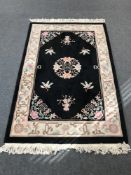 A fringed Chinese style rug on black ground