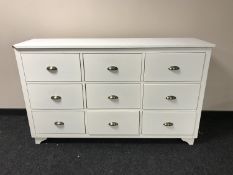 A white nine drawer chest with metal handles