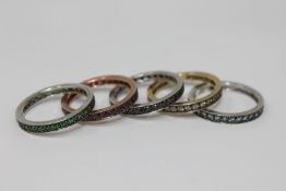 A suite, or stack, of five 9ct gold eternity rings, each set rubies, sapphires, emeralds,