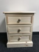 An unfinished reclaimed pine three drawer bedside chest