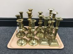 A tray containing six pairs of brass candlesticks