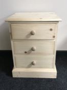 An unfinished pine three drawer bedside chest