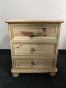 An unfinished pine three drawer bedside chest