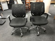 A pair of adjustable swivel office armchairs in mesh fabric