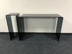 A contemporary black glass console table together with matching plant stand