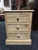 An unfinished reclaimed pine three drawer bedside chest